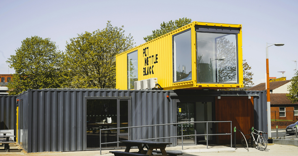 A yellow and black building with a picnic table in front of it.