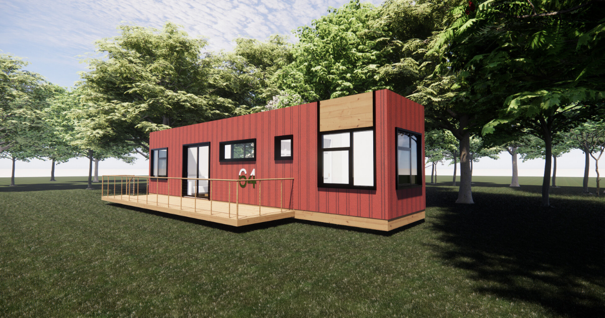 A red house is sitting on top of a lush green field surrounded by trees.