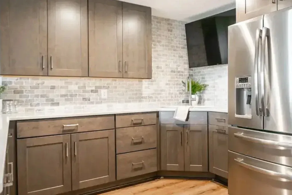 Modern kitchen with gray cabinets, white backsplash, and stainless steel refrigerator.