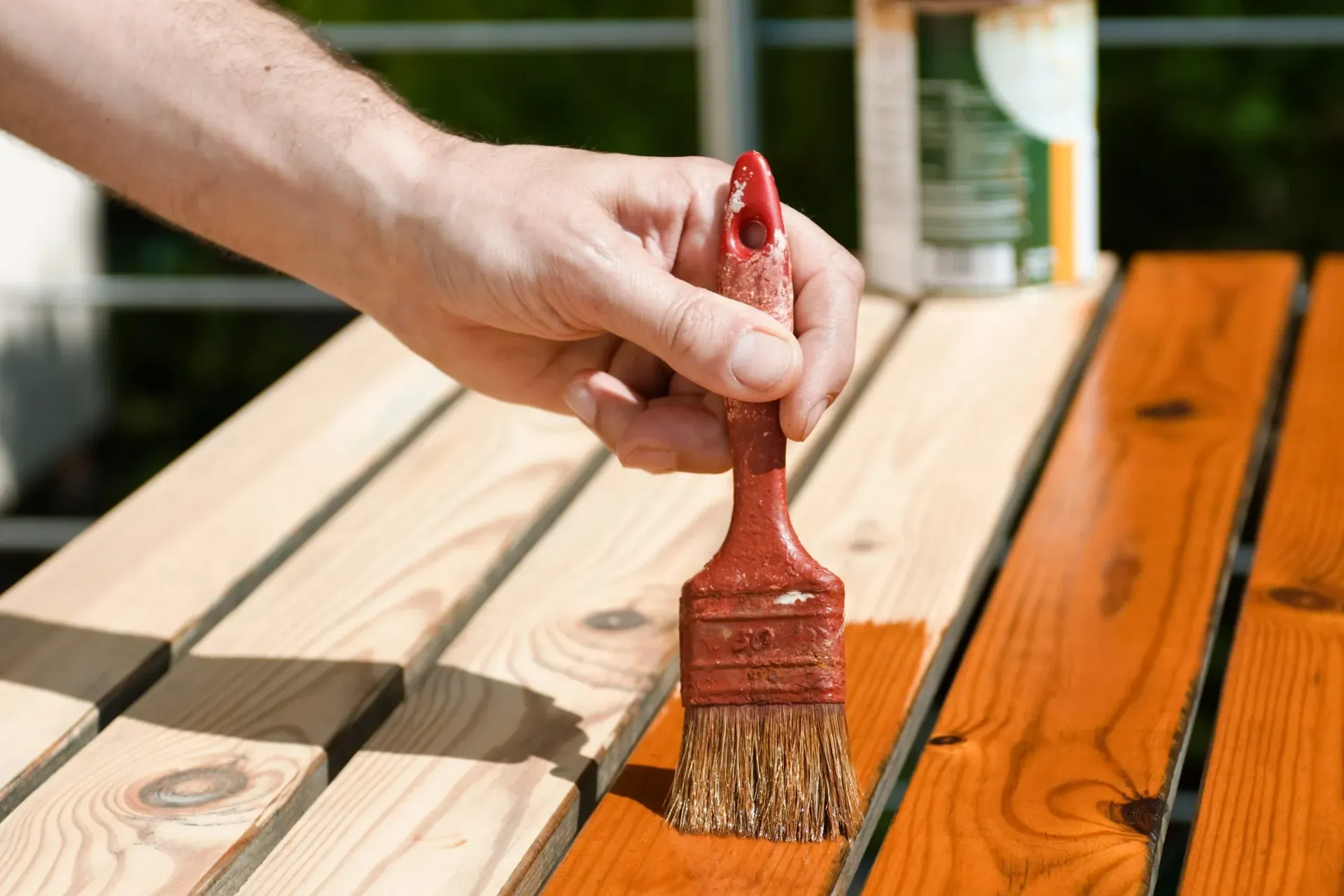 A person is painting a wooden table with a brush.