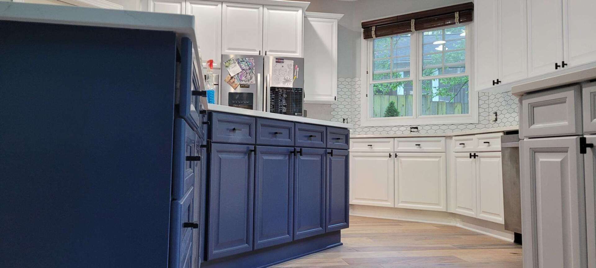 A kitchen with blue cabinets and white cabinets and a large island.