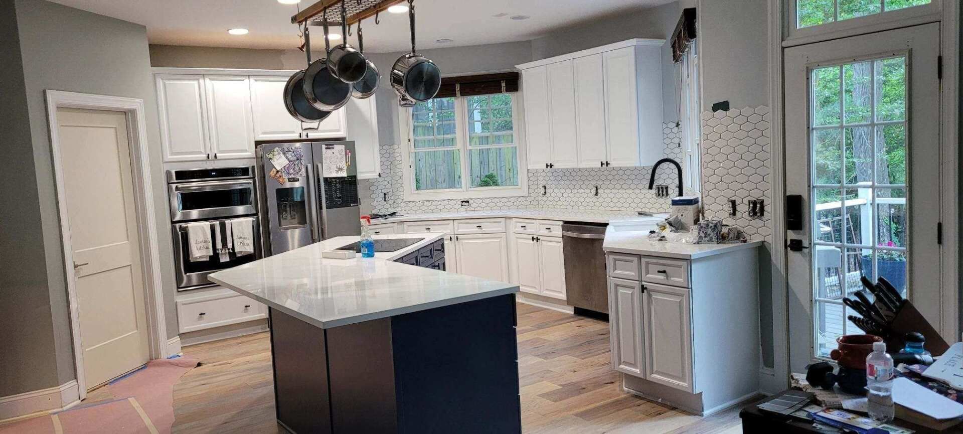A kitchen with white cabinets , stainless steel appliances , and a large island.