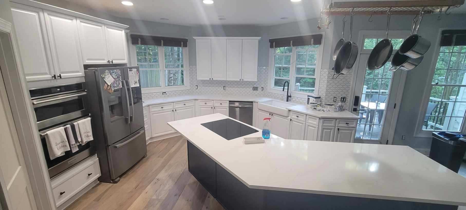 A kitchen with white cabinets , stainless steel appliances , and a large island.