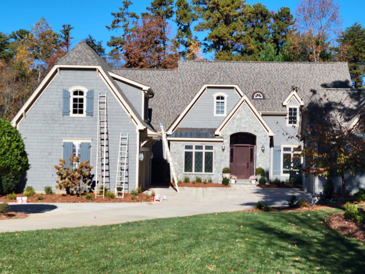 A large house with a ladder in front of it is being painted.