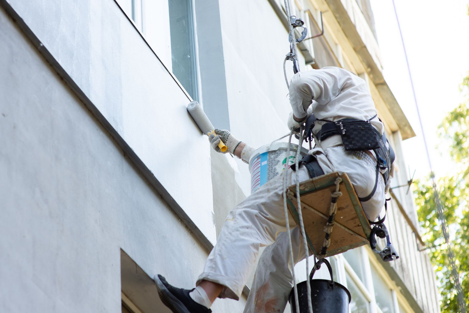 A man is painting a building from a scaffolding.