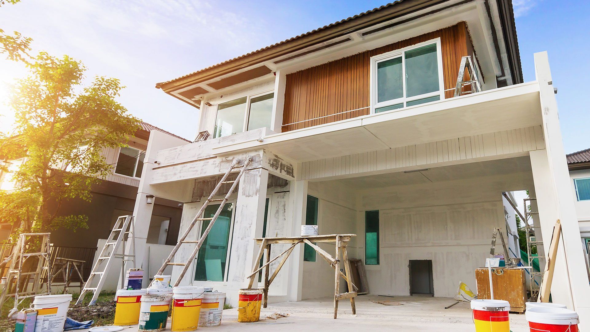 A house is being painted with buckets of paint and a ladder.