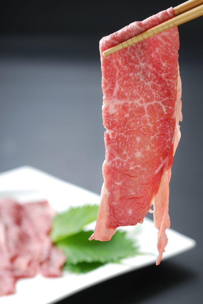 Chopsticks Holding A Piece Of Meat Over A Plate Of Meat — McGrath Meats In Taree, NSW