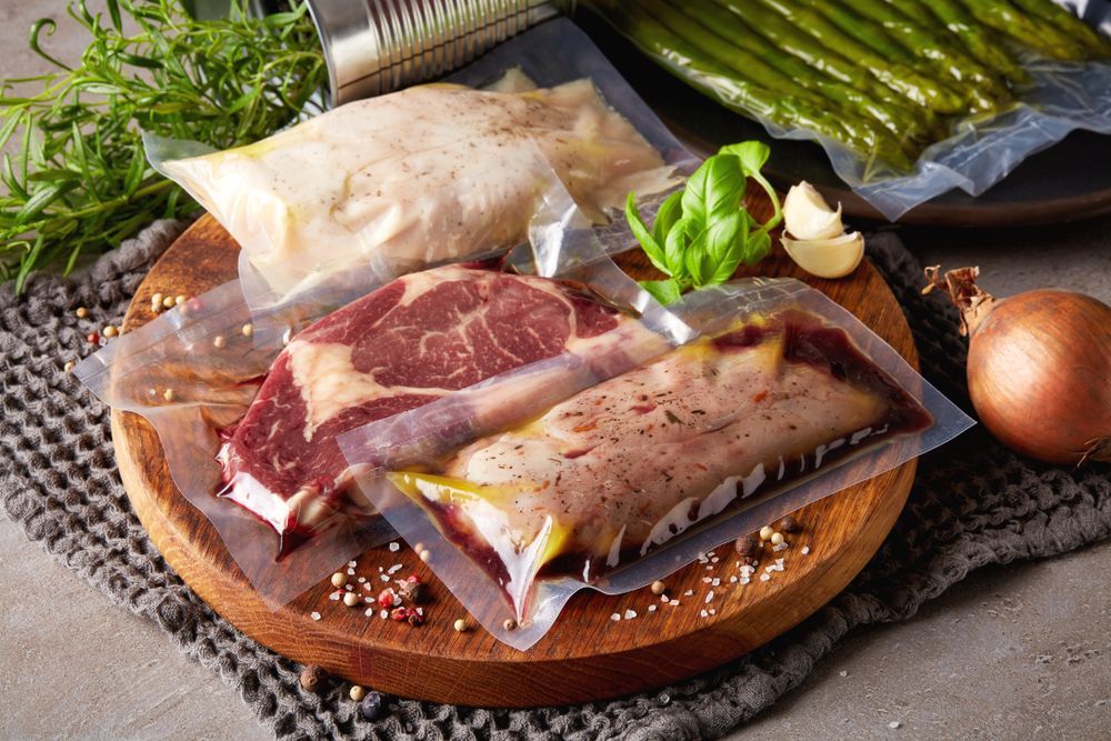 A Wooden Cutting Board Topped With Vacuum Sealed Meat And Vegetables — McGrath Meats In Taree, NSW