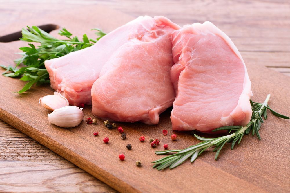 Raw Pork Chops On A Wooden Cutting Board With Herbs And Spices — McGrath Meats In Taree, NSW