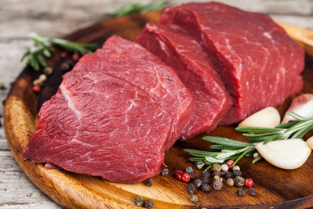 Raw Beef Steaks On A Wooden Cutting Board With Spices — McGrath Meats In Taree, NSW