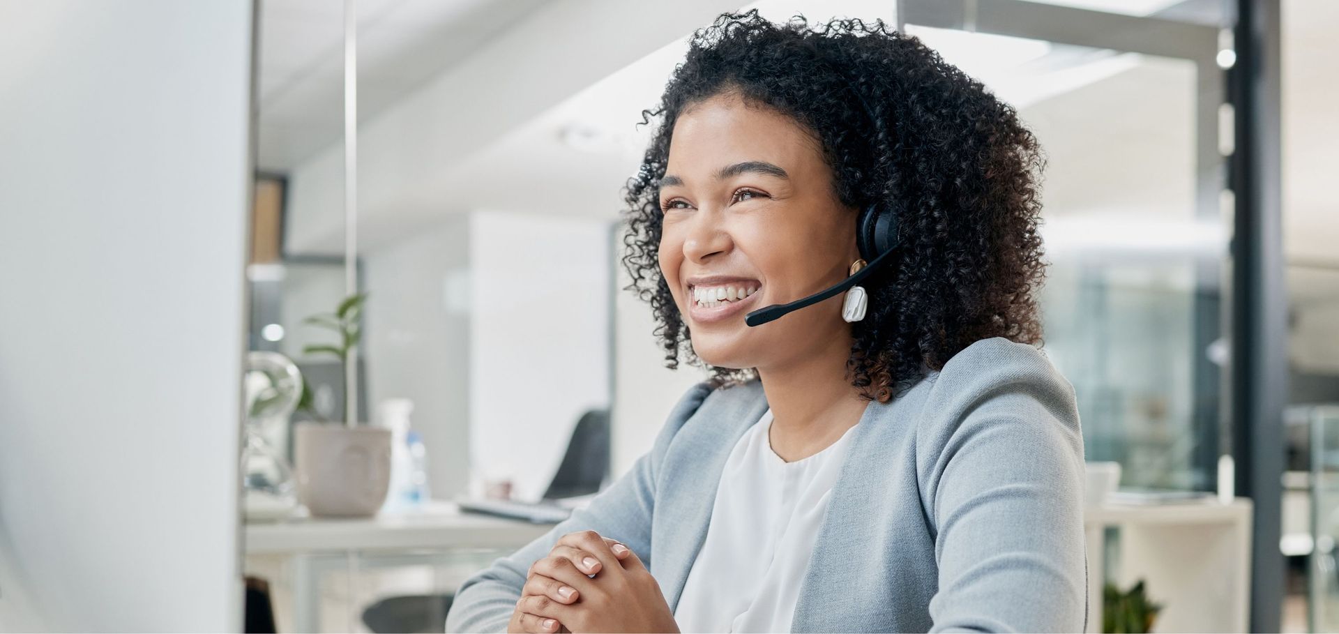 A woman wearing a headset is sitting in front of a computer.