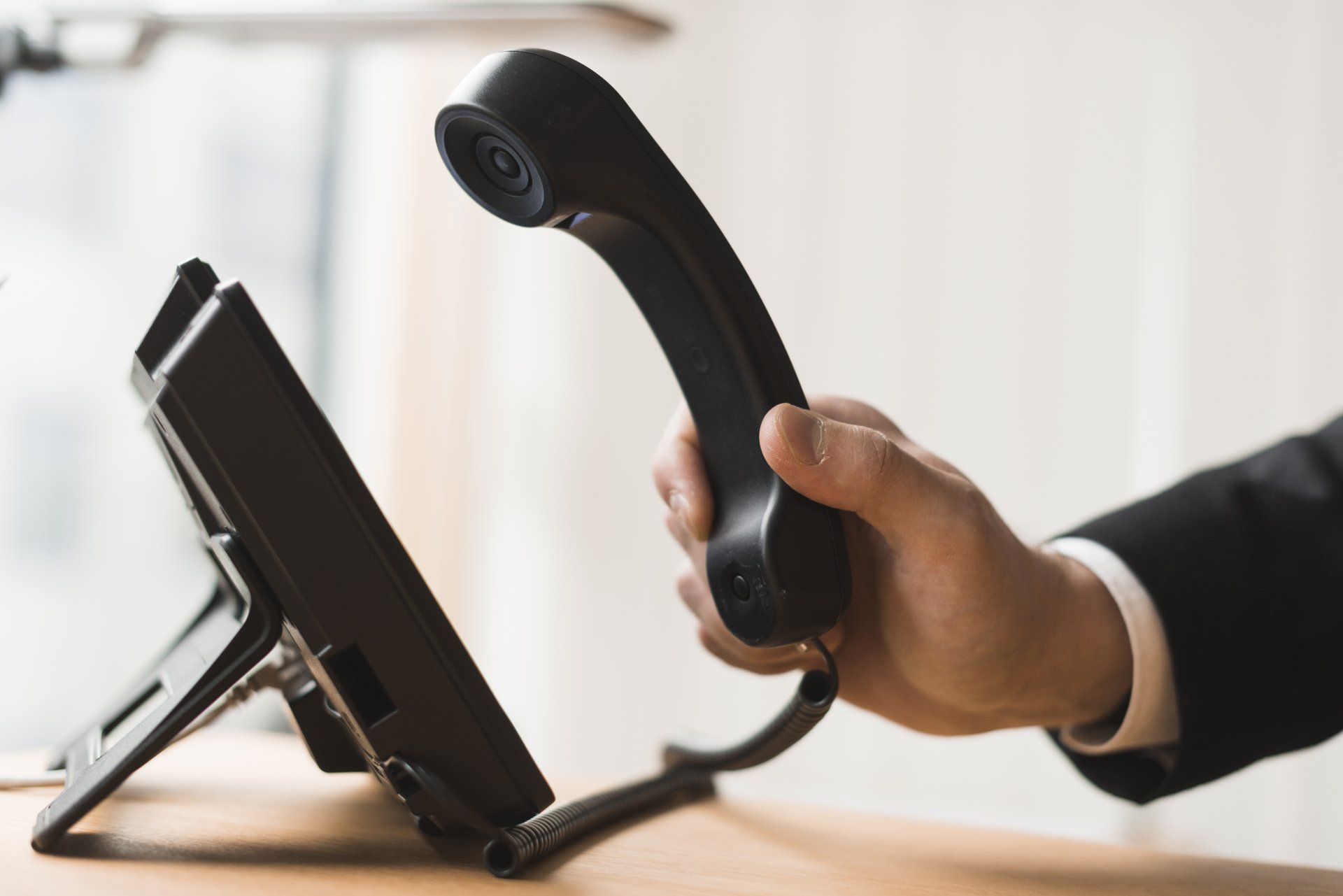 a hand is picking up a phone powered by business VoIP phone solutions