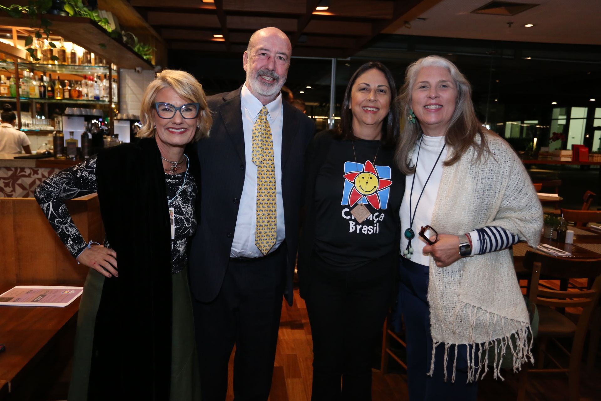 Four people smiling together indoors; restaurant setting.