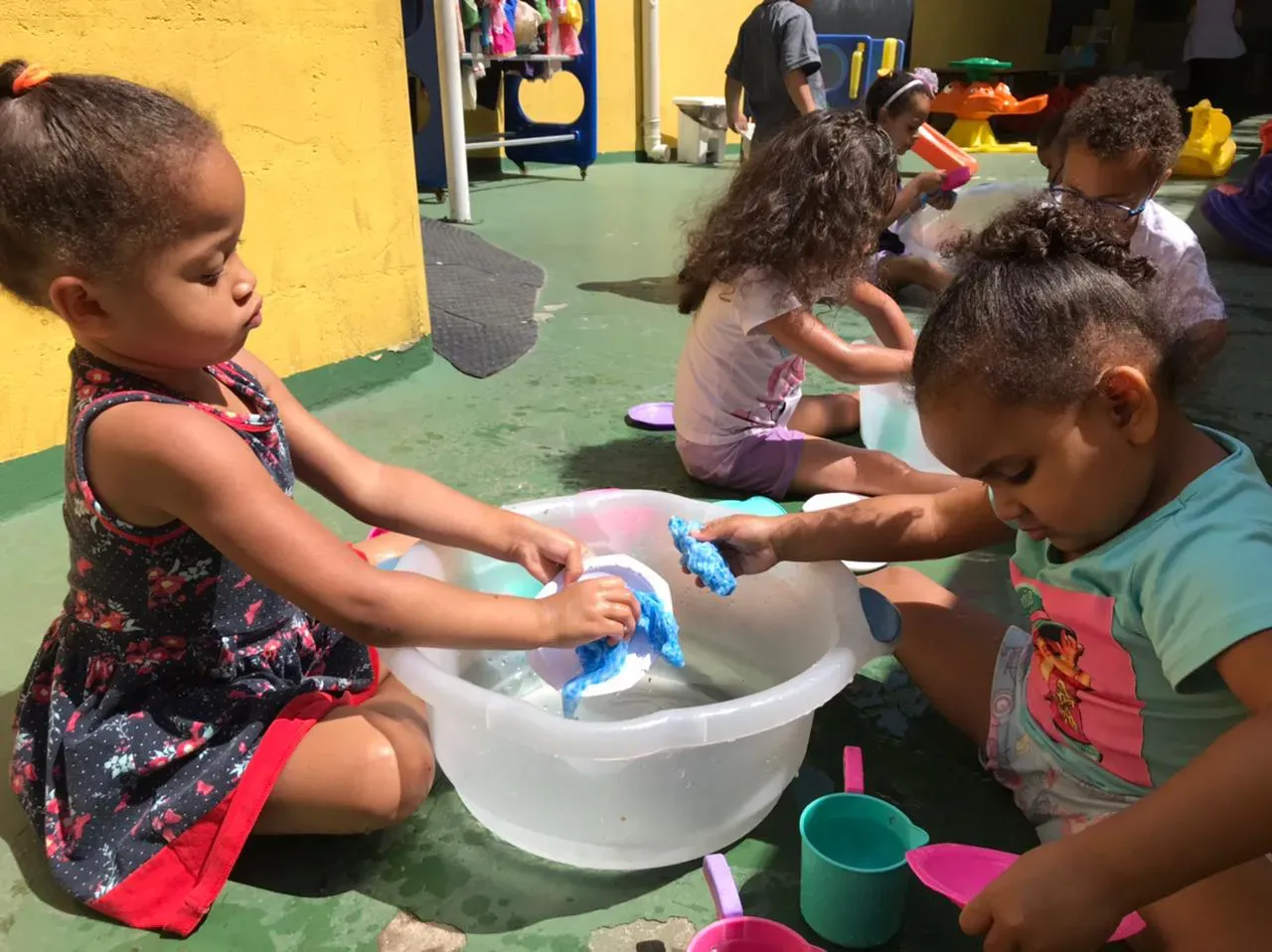 Um grupo de meninas está brincando com brinquedos em uma tigela.