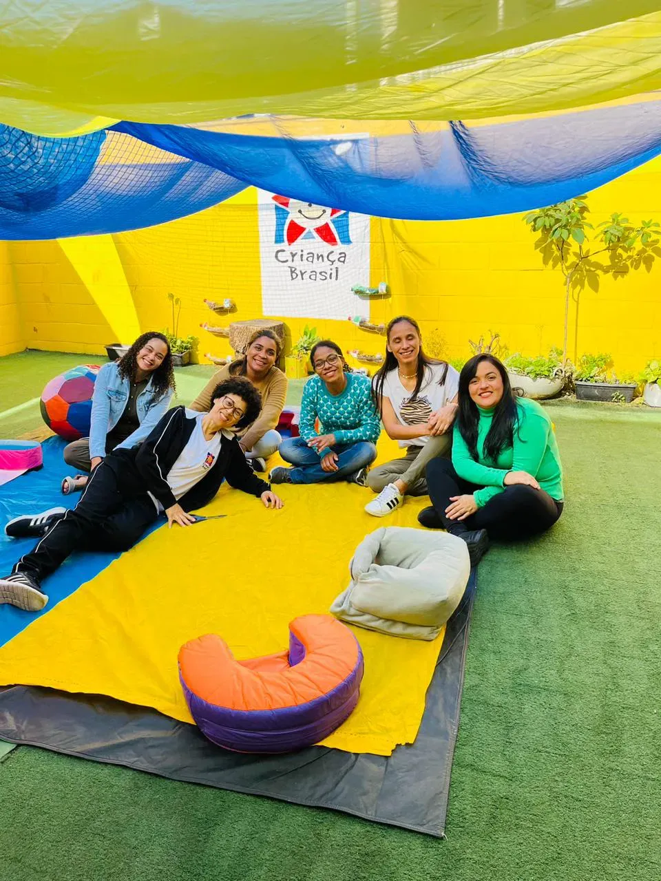 Um grupo de pessoas está sentado em um cobertor na grama.