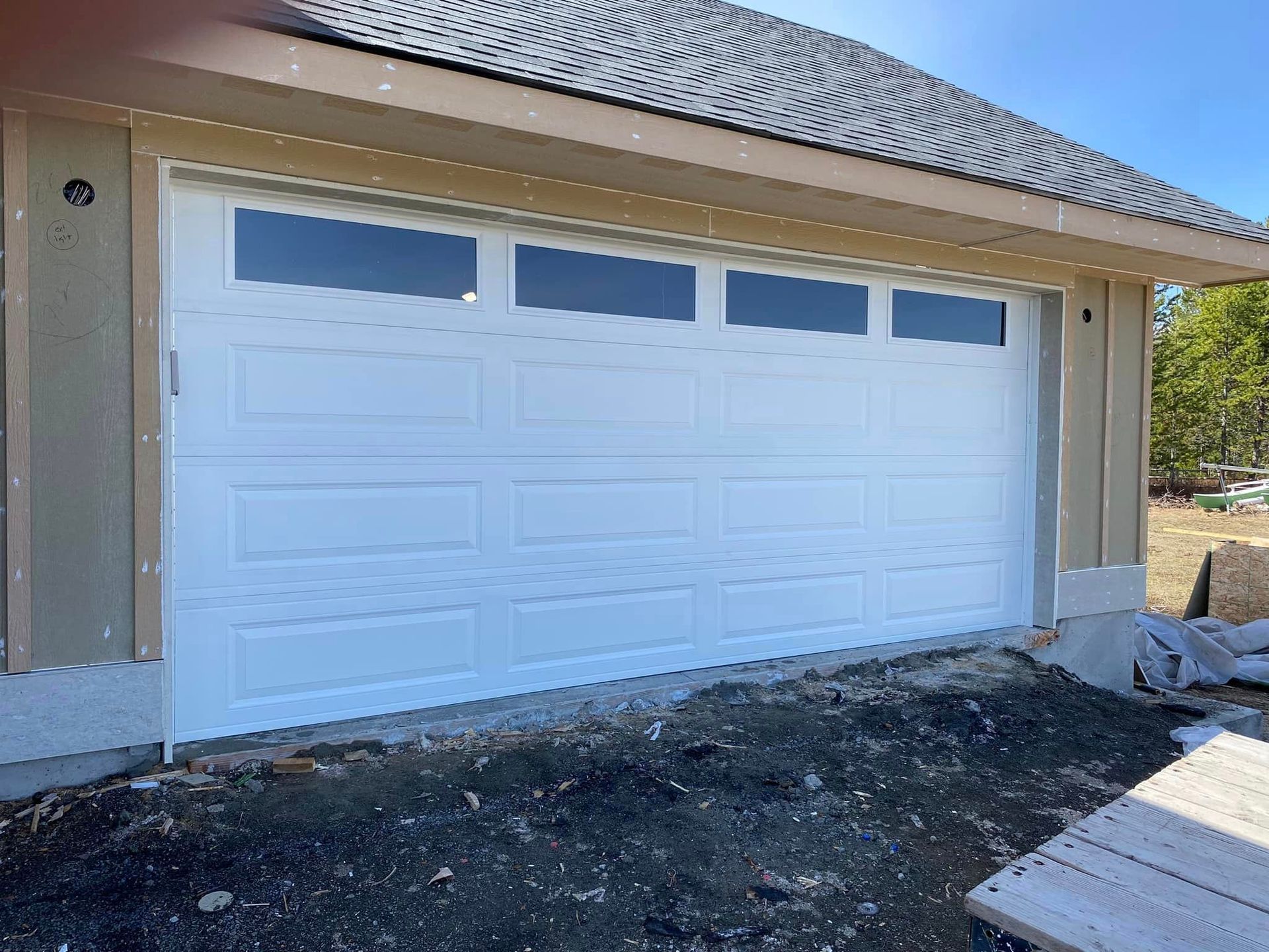 A white garage door is sitting on the side of a house.