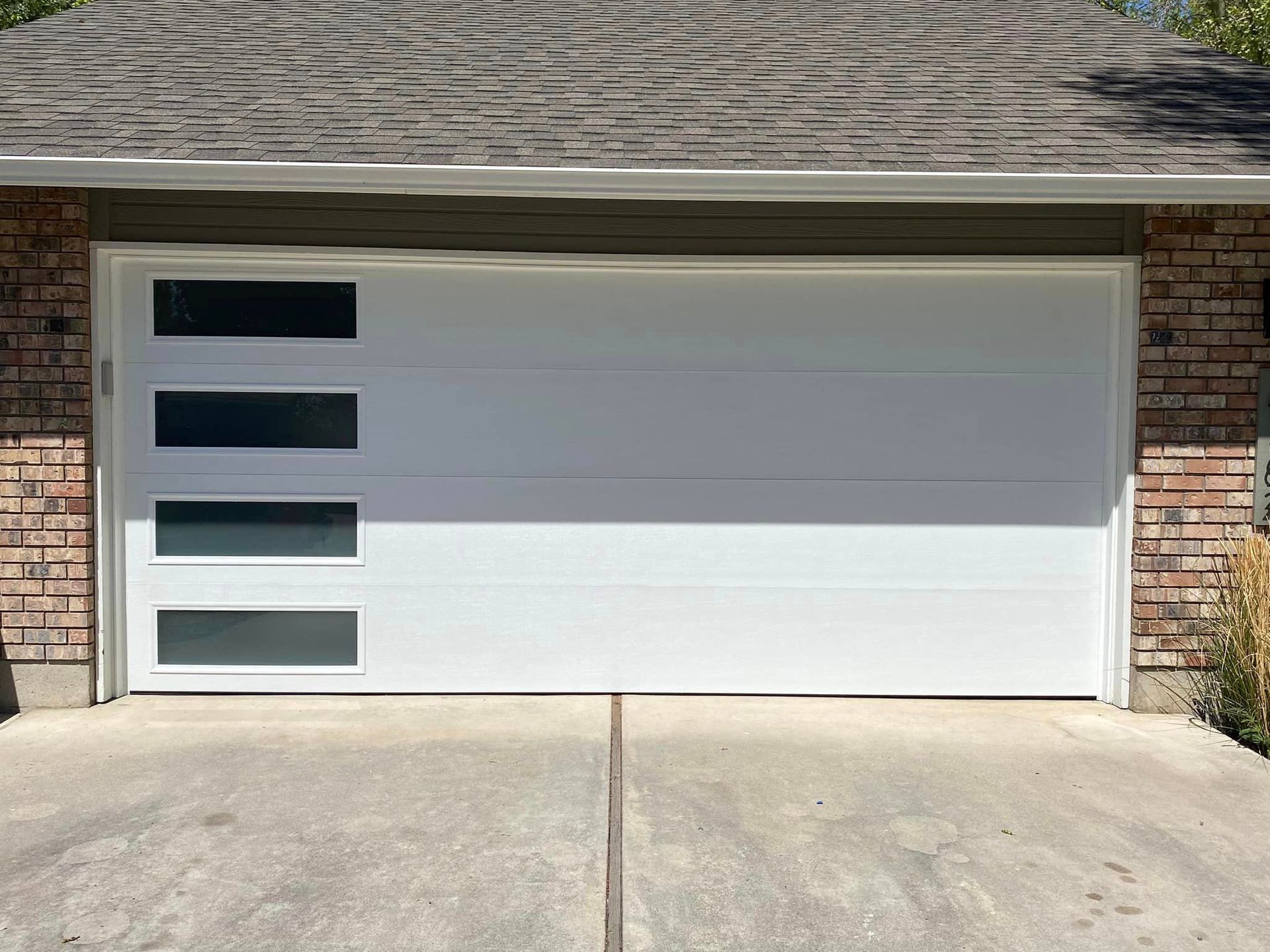 A white garage door is sitting in front of a brick house.