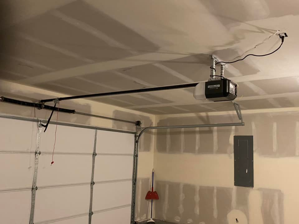 A garage door motor is hanging from the ceiling of a garage.