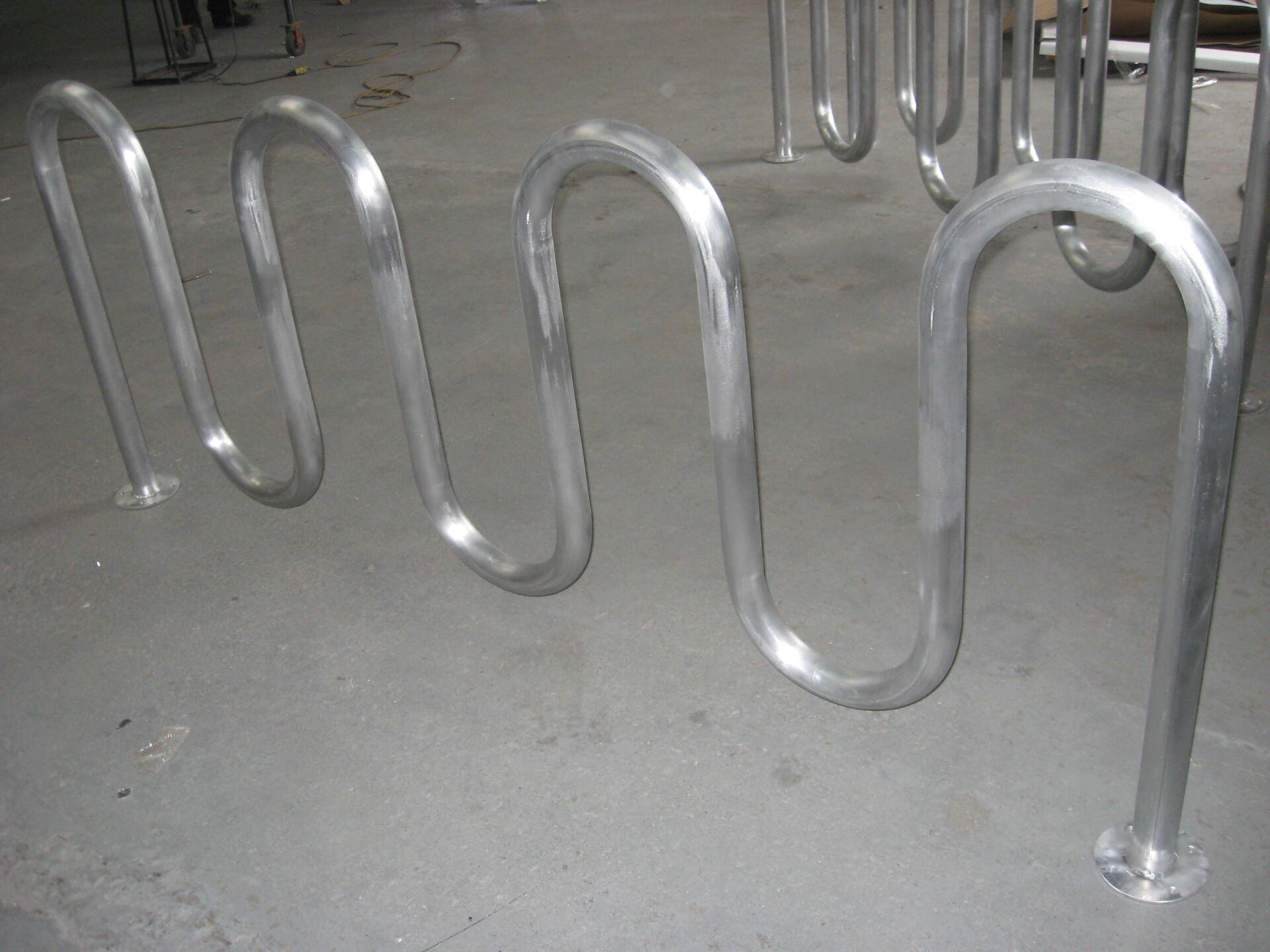 Une rangée de supports à vélos métalliques en forme de spirale sur un sol en béton.