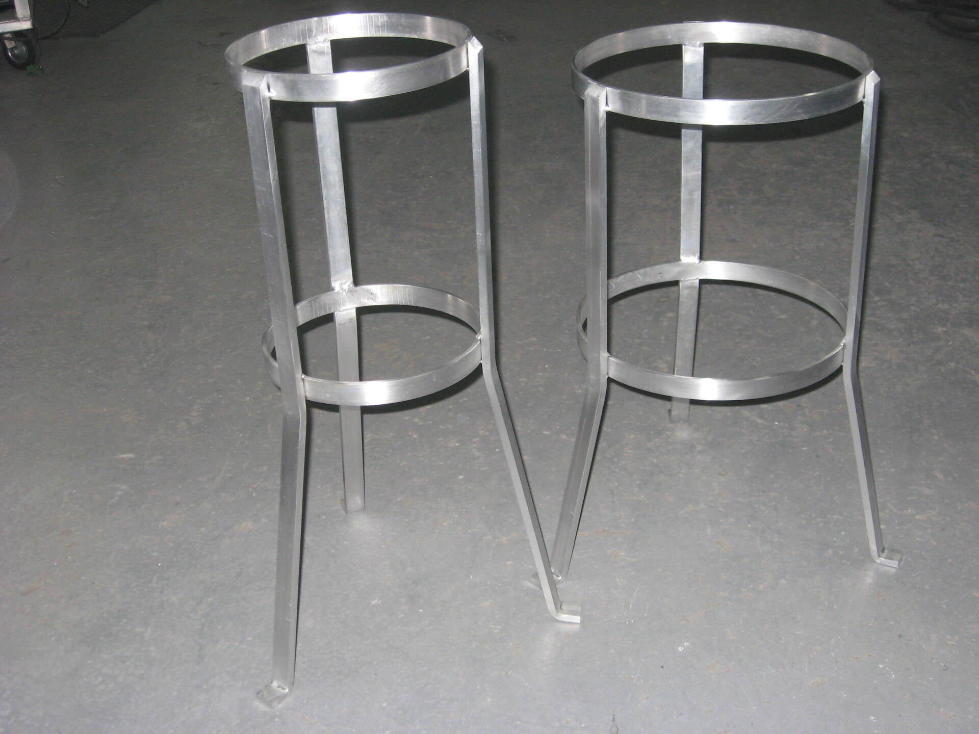 Deux tabourets en métal sont posés sur un sol en béton