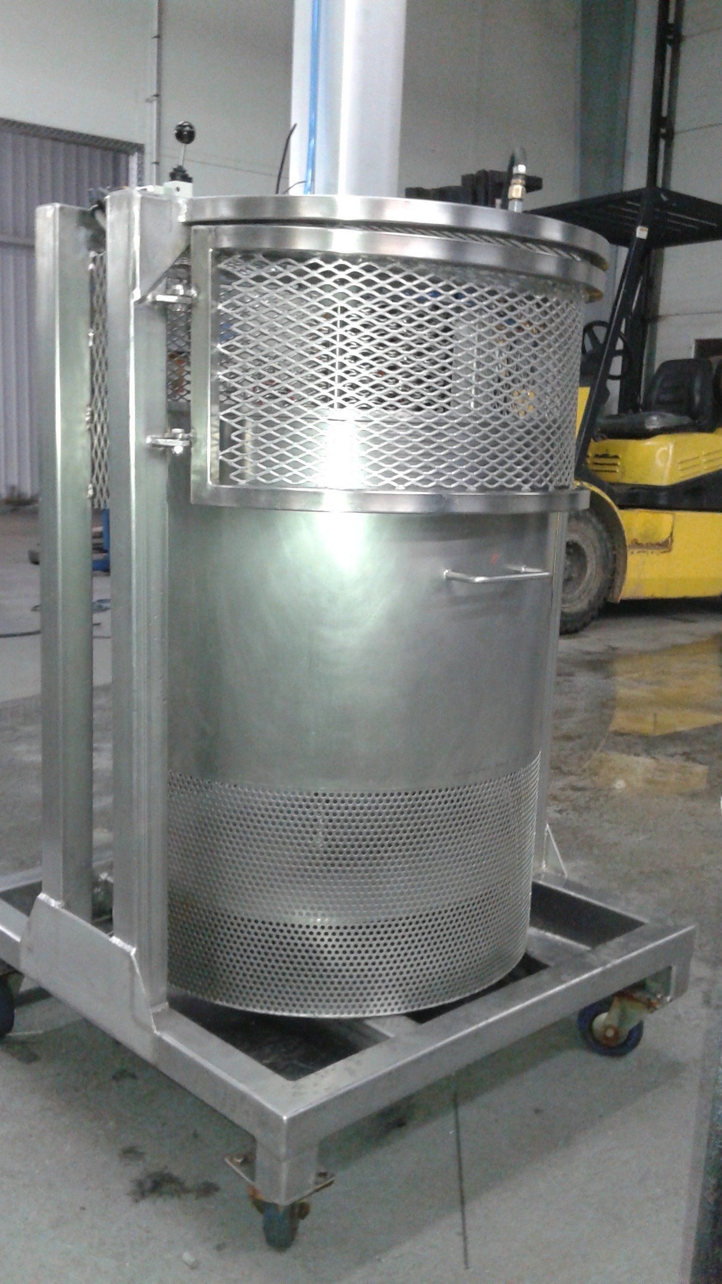 Un grand conteneur en acier inoxydable est posé sur un chariot dans un entrepôt.