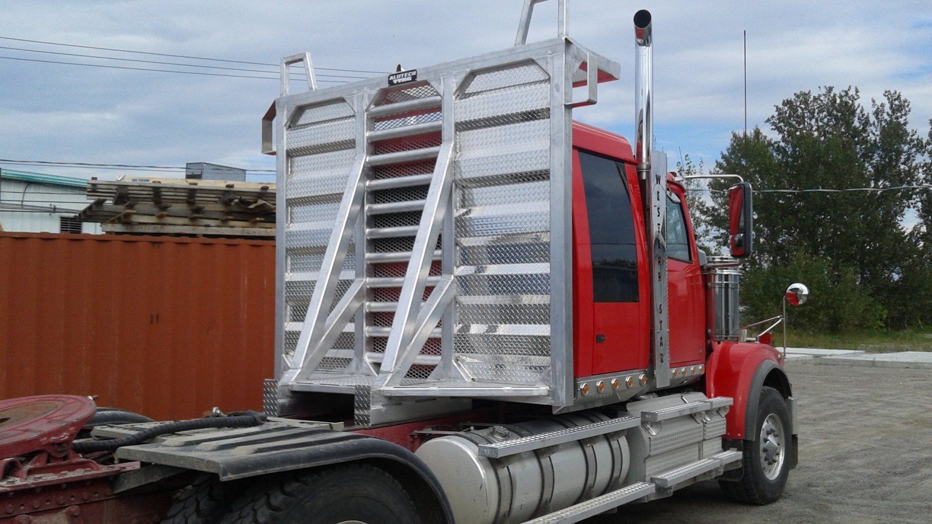 Un semi-remorque rouge auquel est attachée une remorque est garé dans un parking.