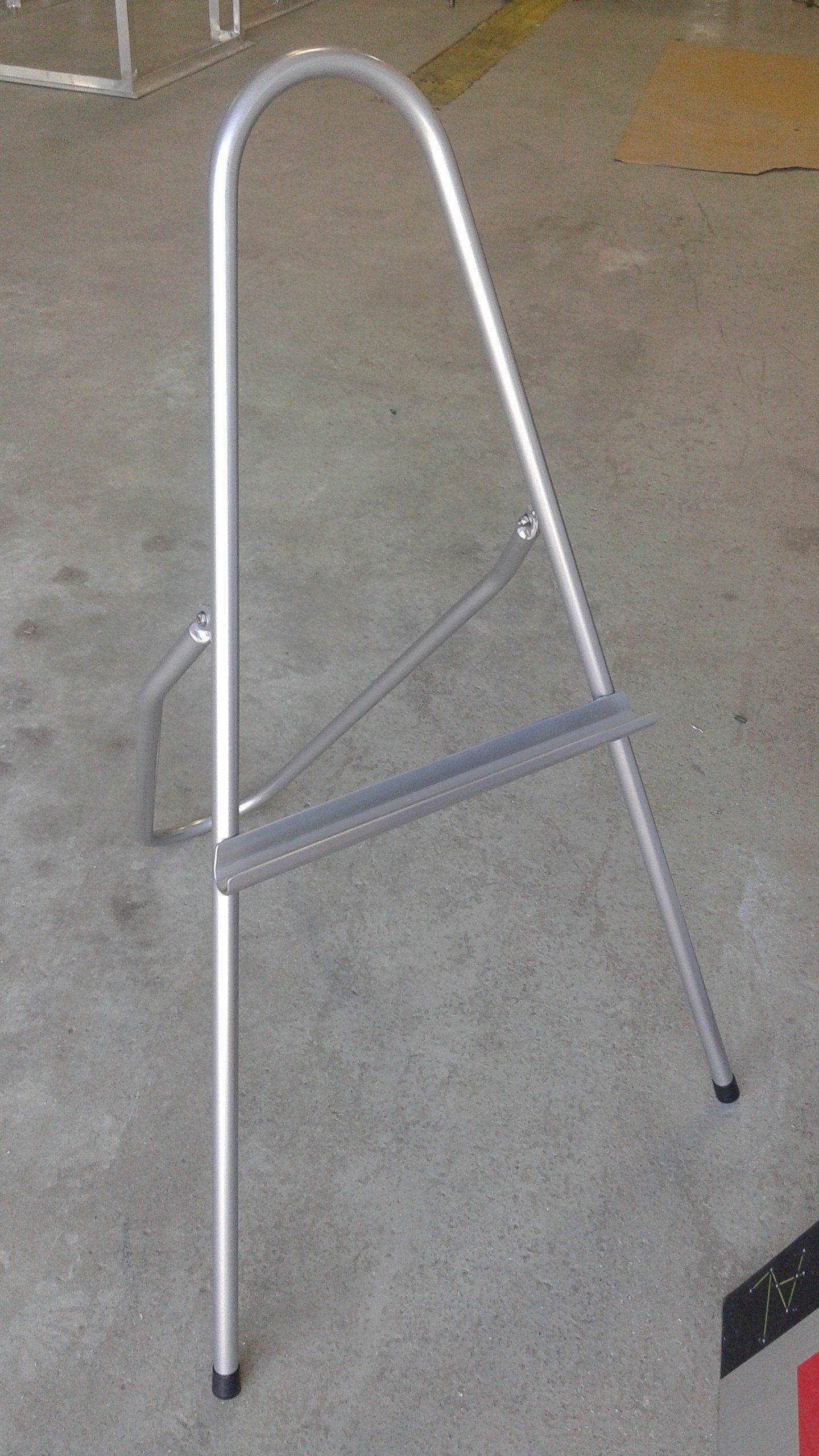 Un chevalet en métal repose sur un sol en béton.