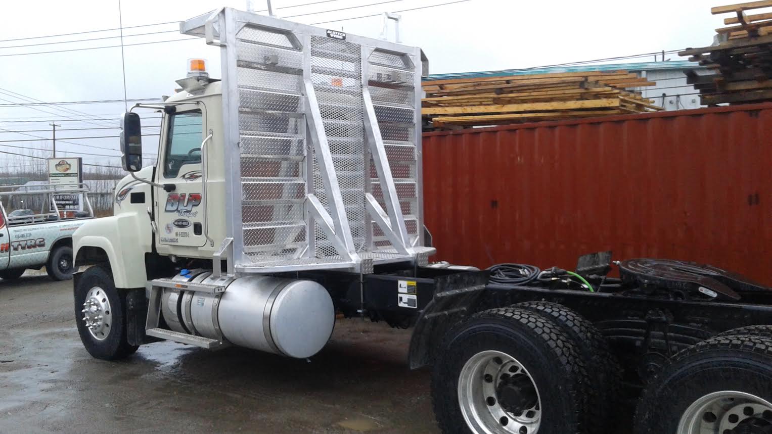 Un semi-remorque est garé à côté d'un conteneur rouge.