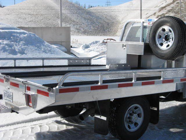 Un camion en aluminium avec une roue de secours à l'arrière est garé dans la neige