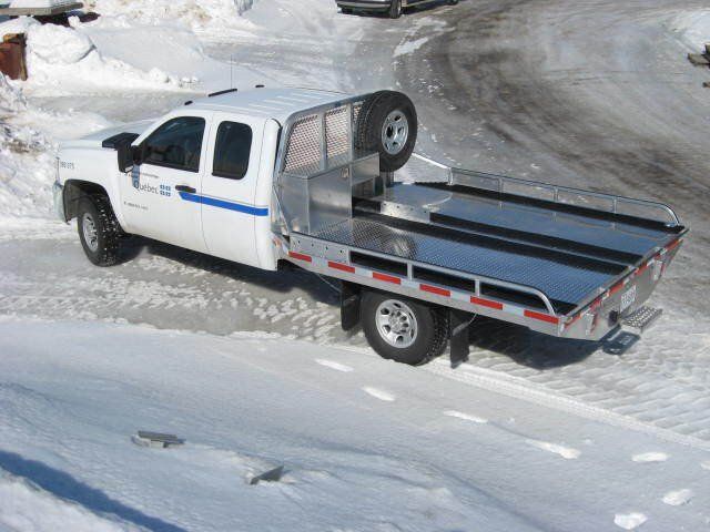 Un camion blanc avec plateau est garé dans la neige