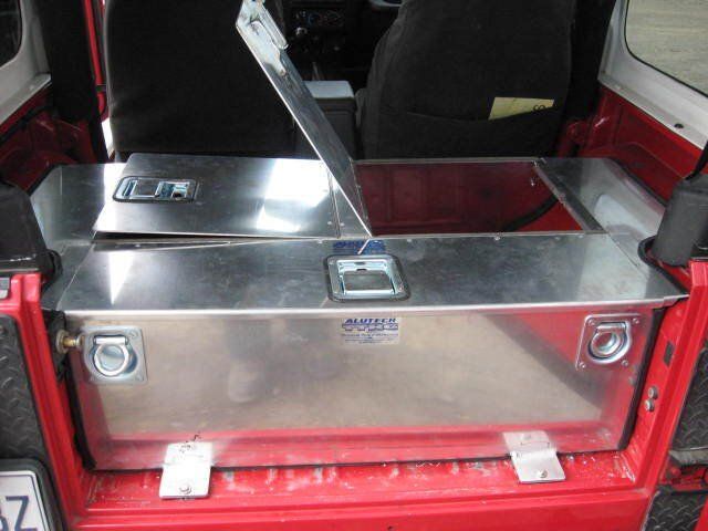 Une jeep rouge avec une boîte à outils en acier inoxydable à l'arrière