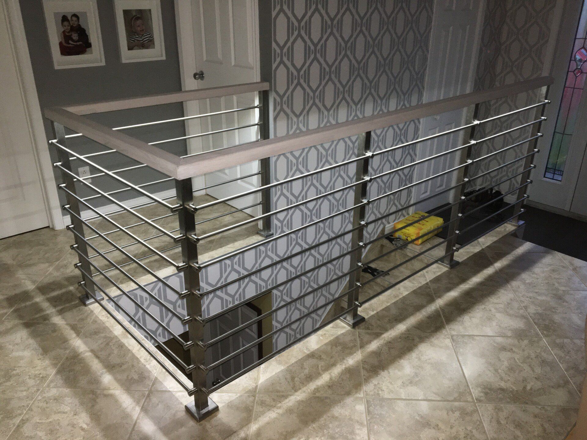 Un escalier avec un garde-corps en inox et une main courante en bois.