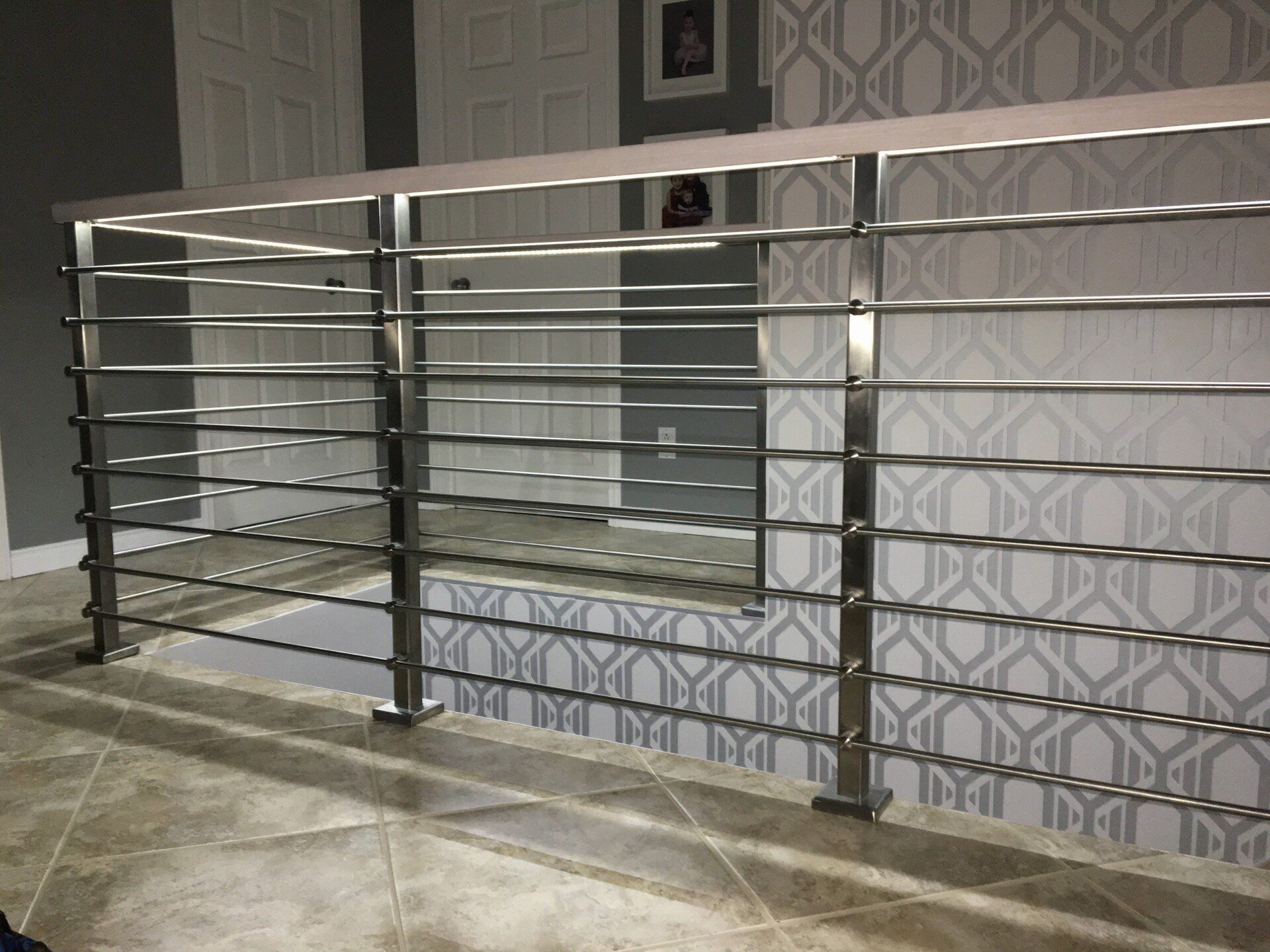 Une balustrade en inox dans une pièce avec un papier peint à motifs