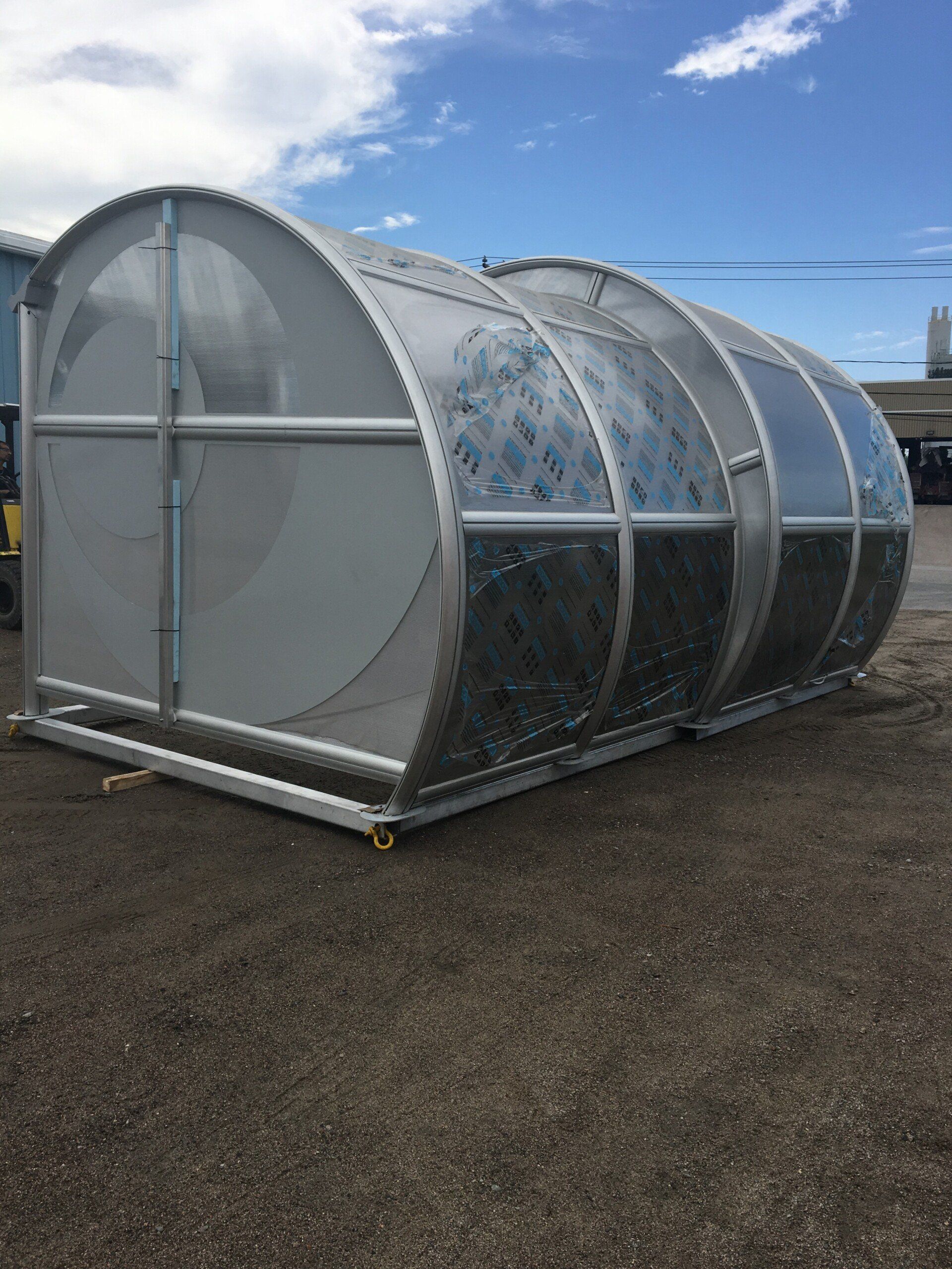 Une grande structure métallique repose dans la terre dans un parking.