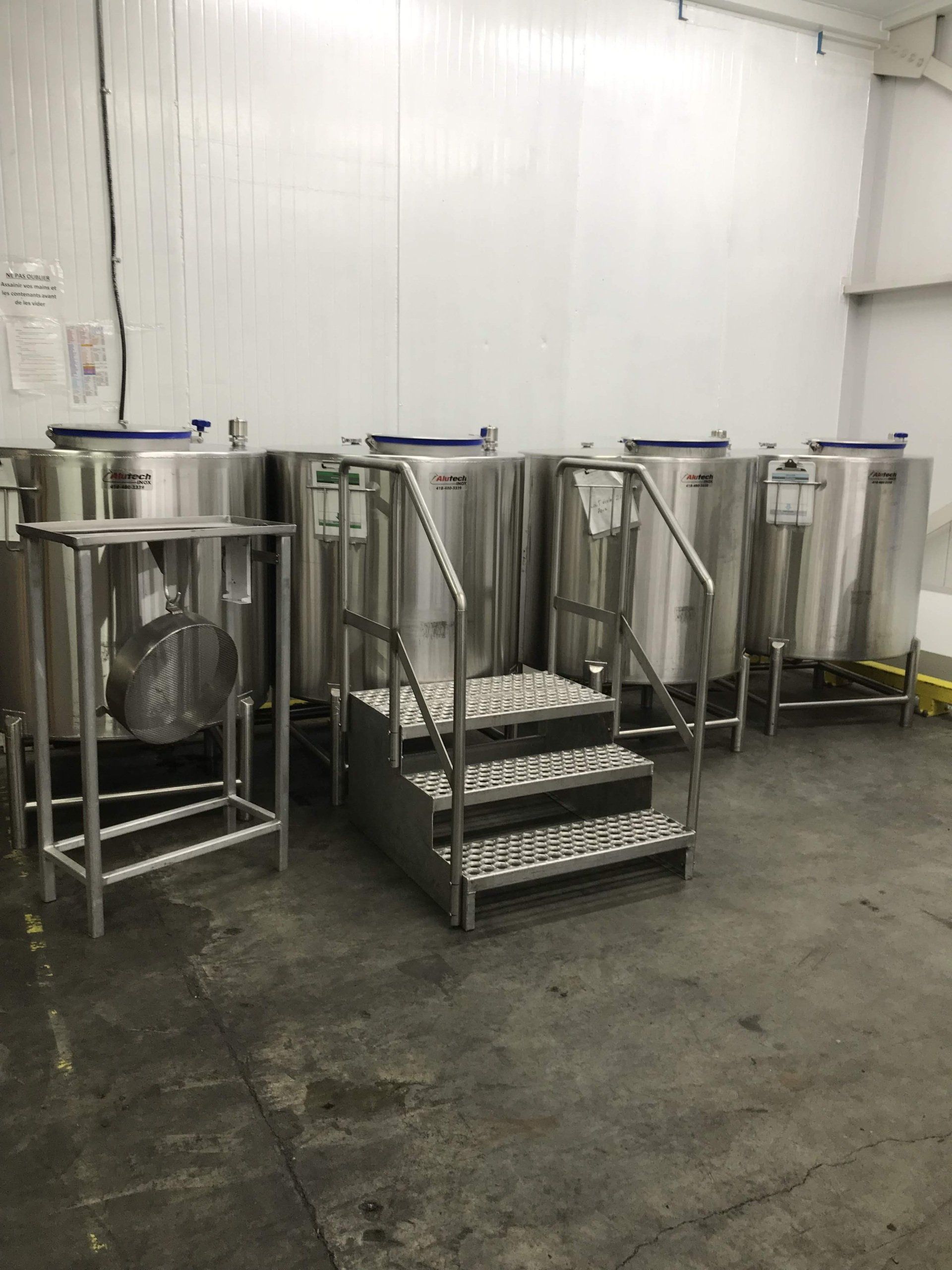Une pièce remplie de cuves et d'escaliers en acier inoxydable.