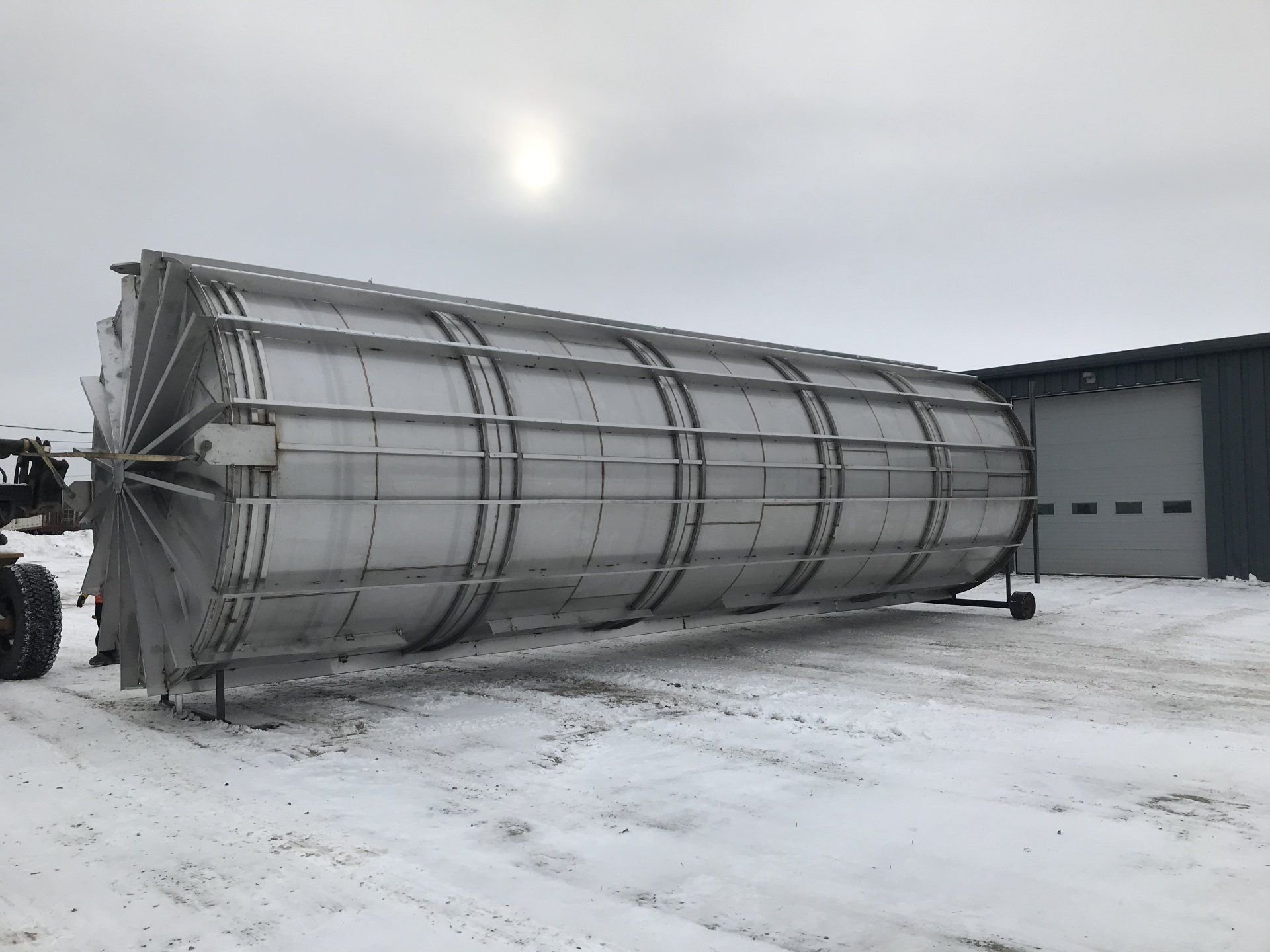 Un grand réservoir en acier inoxydable repose dans la neige devant un immeuble.