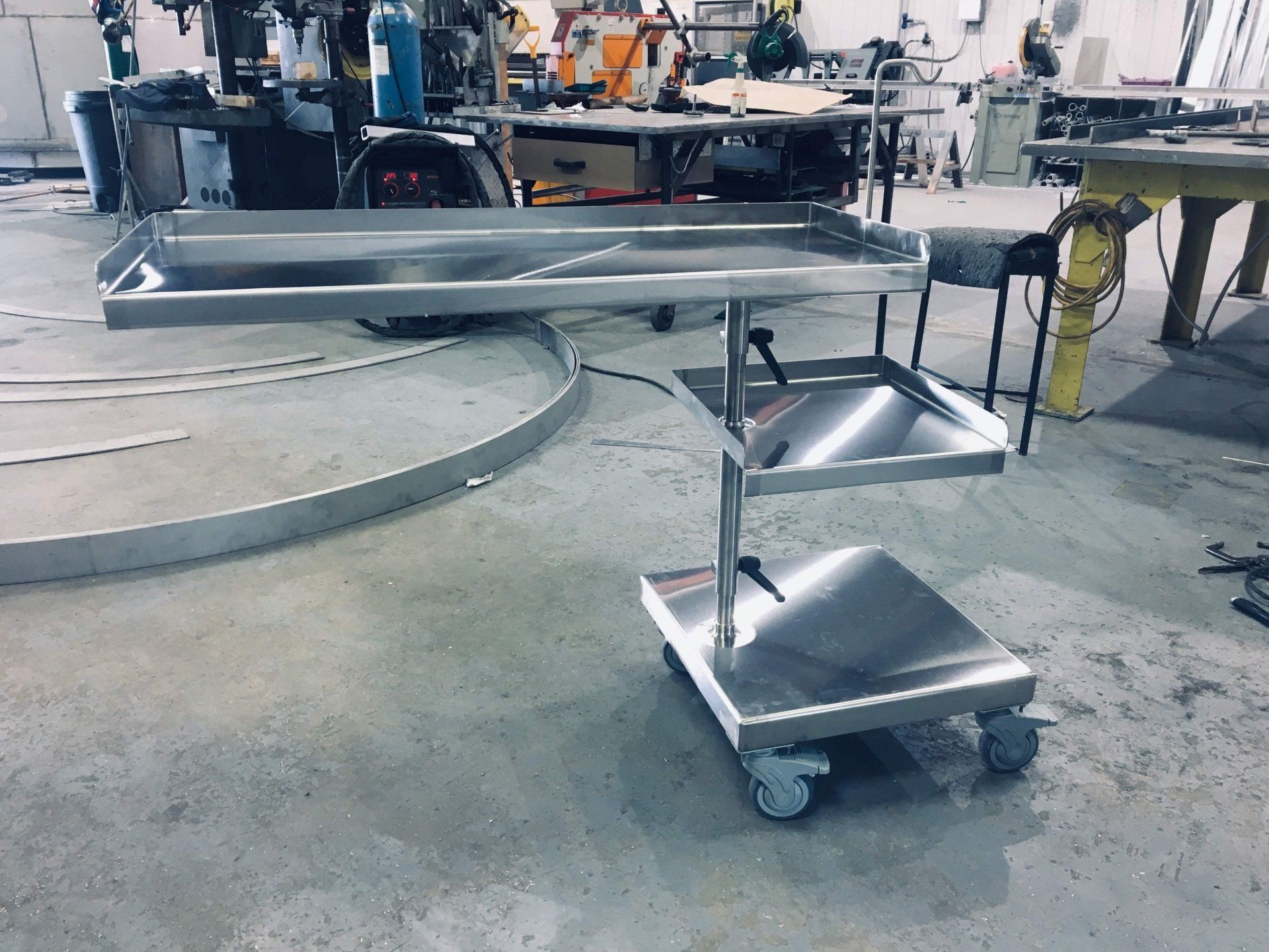 Un chariot en acier inoxydable avec trois étagères et roues