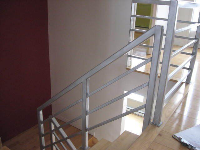 Un escalier avec une rampe en métal et des marches en bois