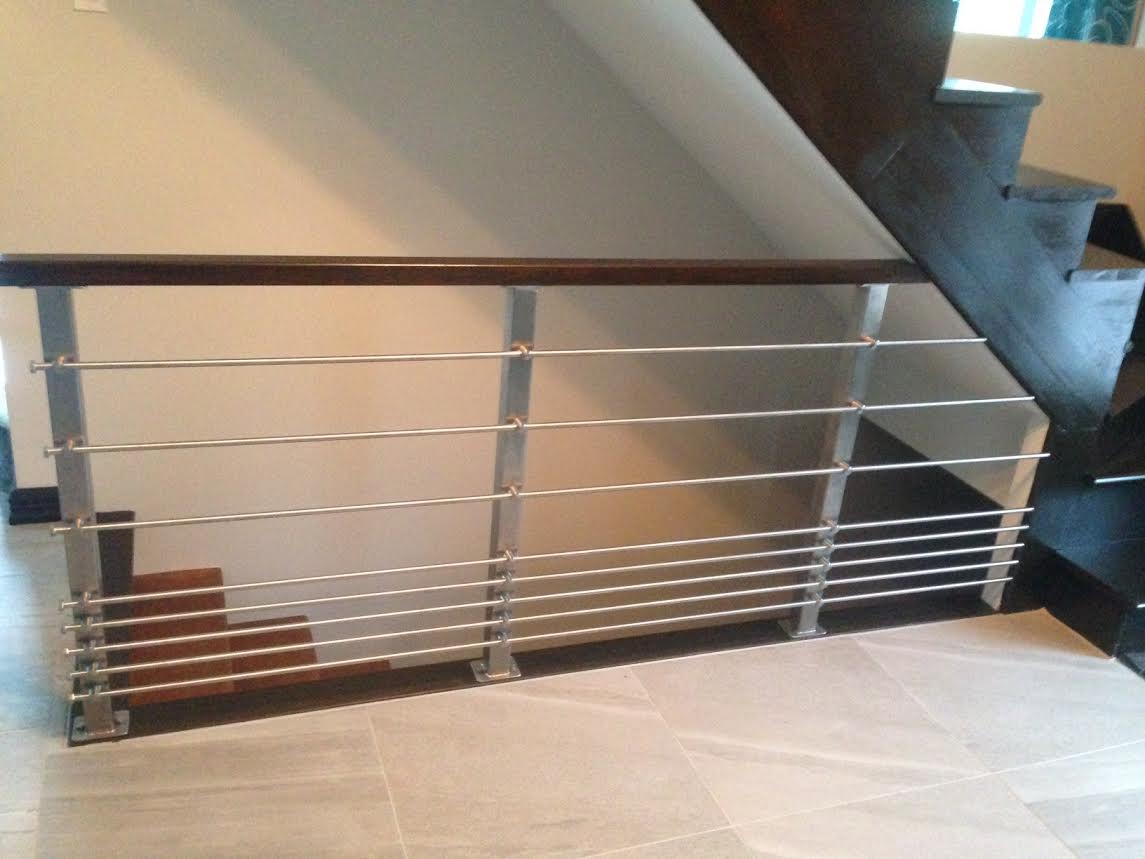 Un escalier avec un garde-corps en inox et une main courante en bois