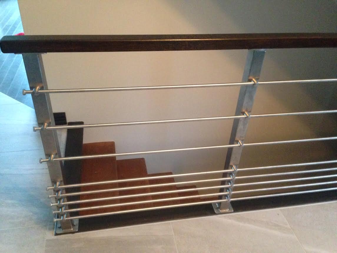 Un escalier avec une rampe en métal et une main courante en bois