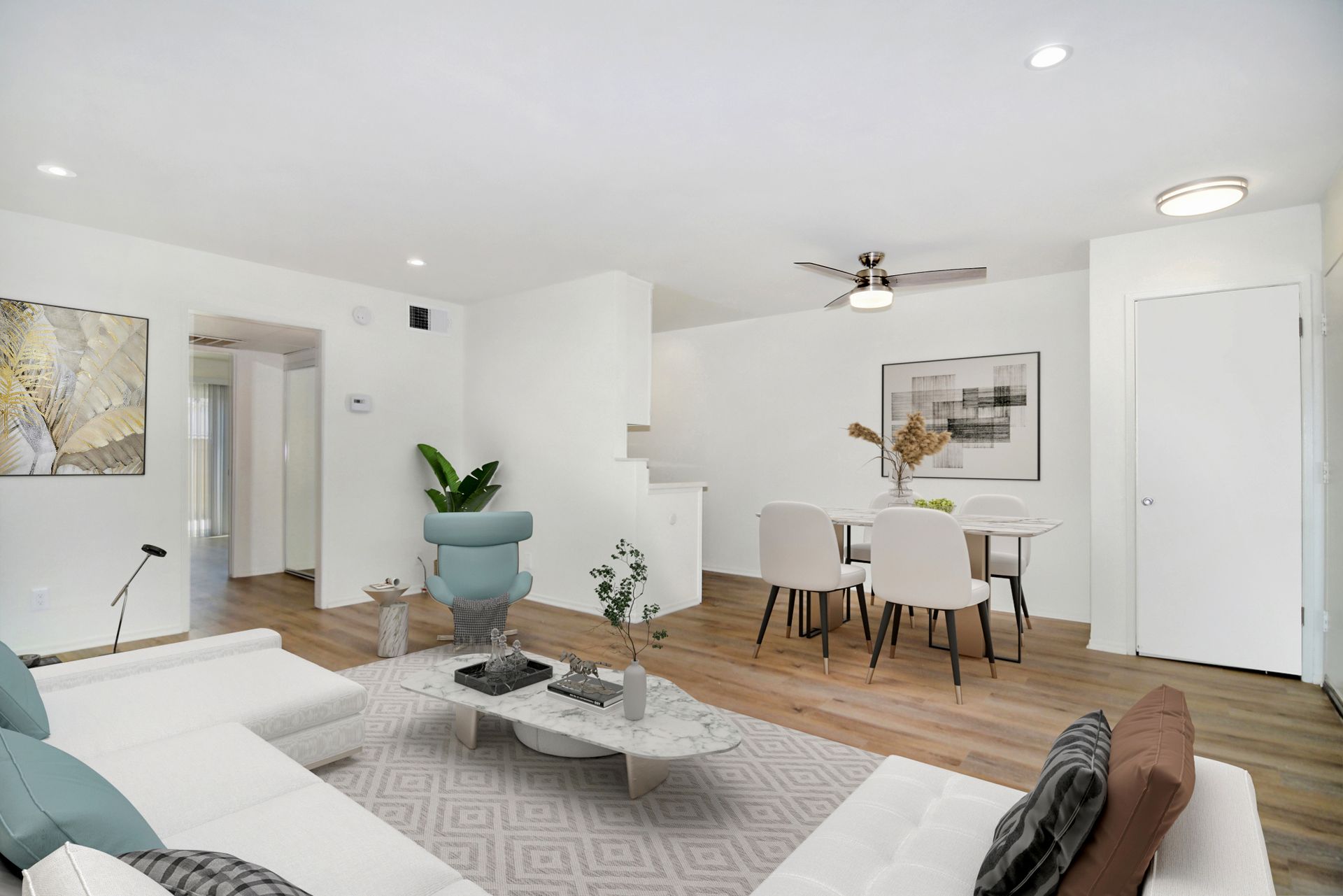 a living room with a couch , table , chairs and a ceiling fan .