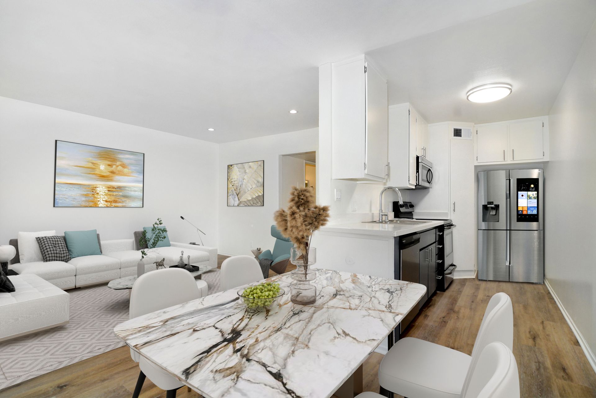 a living room with a marble table and chairs and a kitchen with a stainless steel refrigerator .