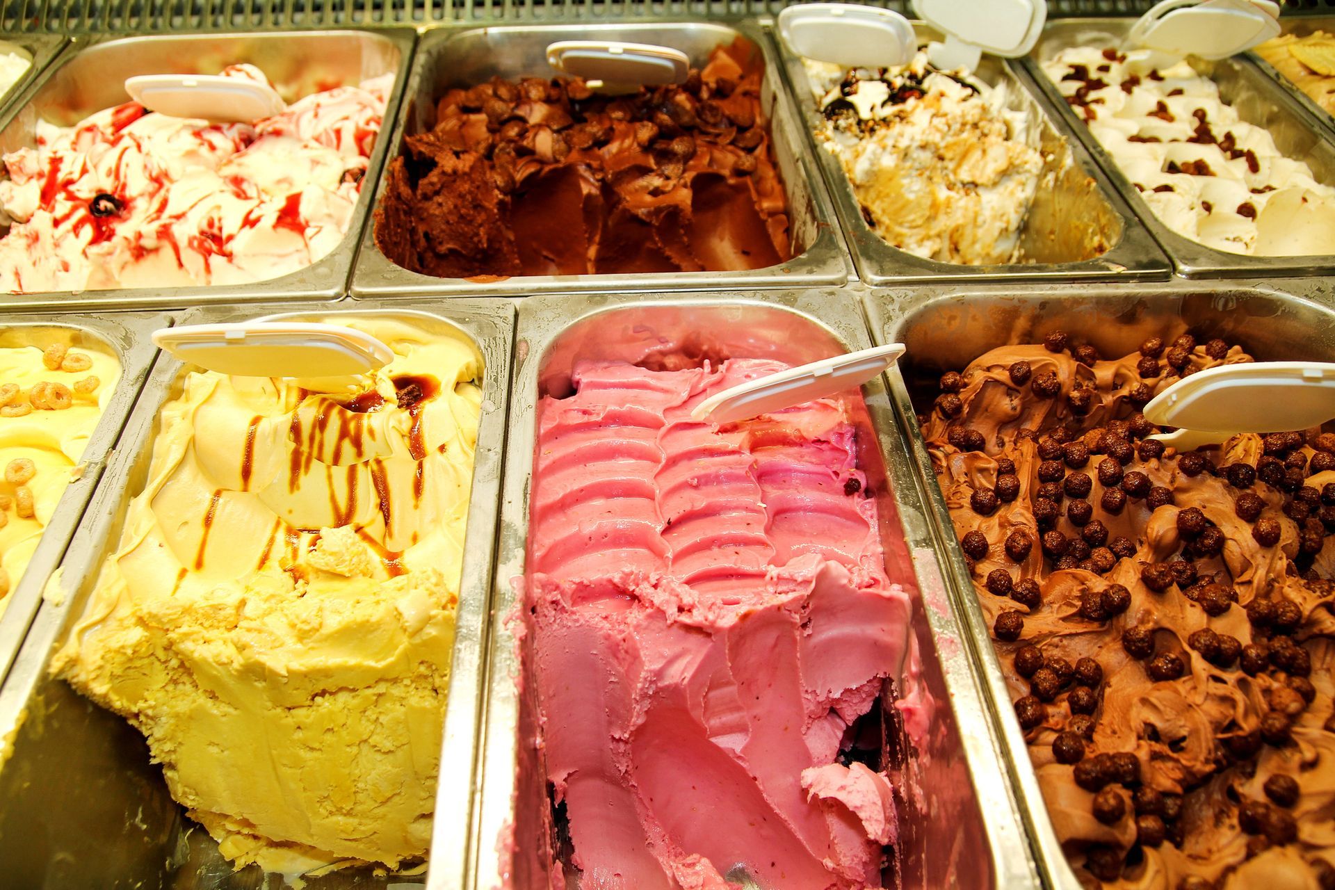 Vetrina con diverse vaschette di gelato colorato.