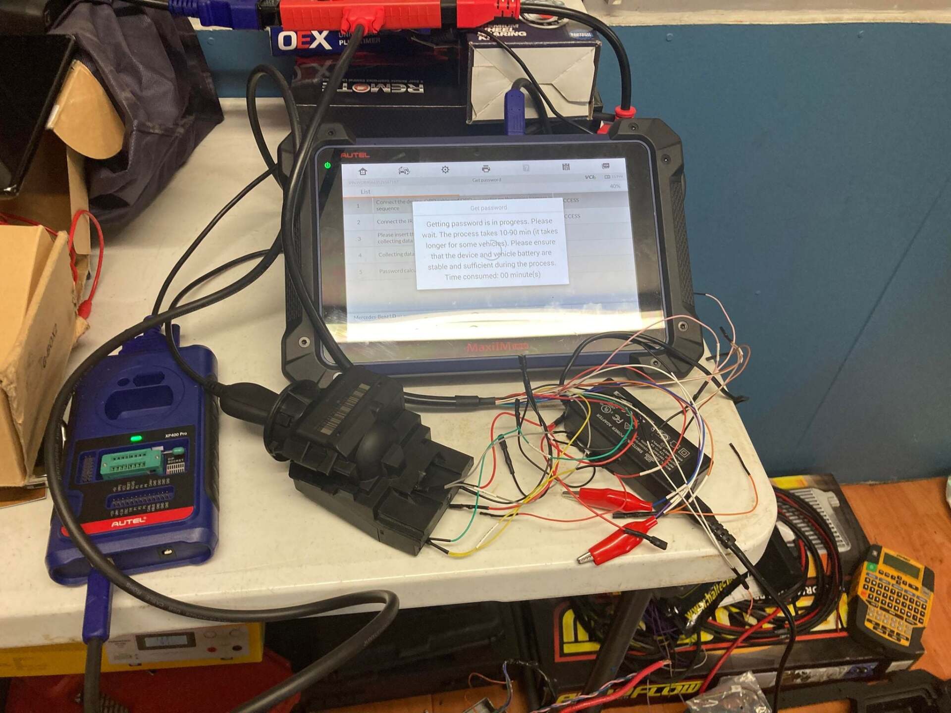 A car diagnostic setup with a tablet, blue reader, and various wires on a table.— Locksmiths In Thuringowa Central, QLD