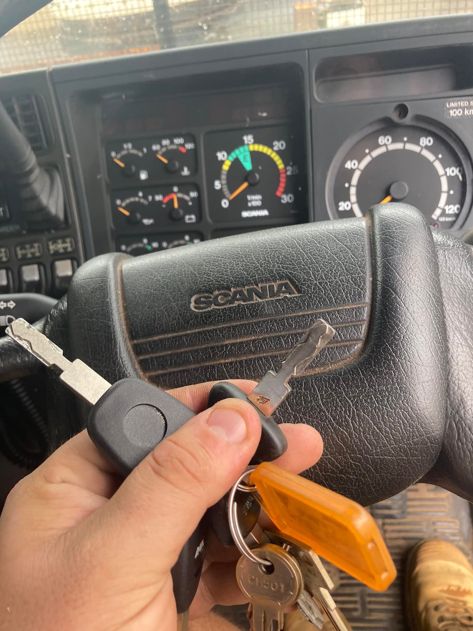 Hand holding keys in front of a Scania truck dashboard, visible gauges and steering wheel.— Locksmiths In Thuringowa Central, QLD