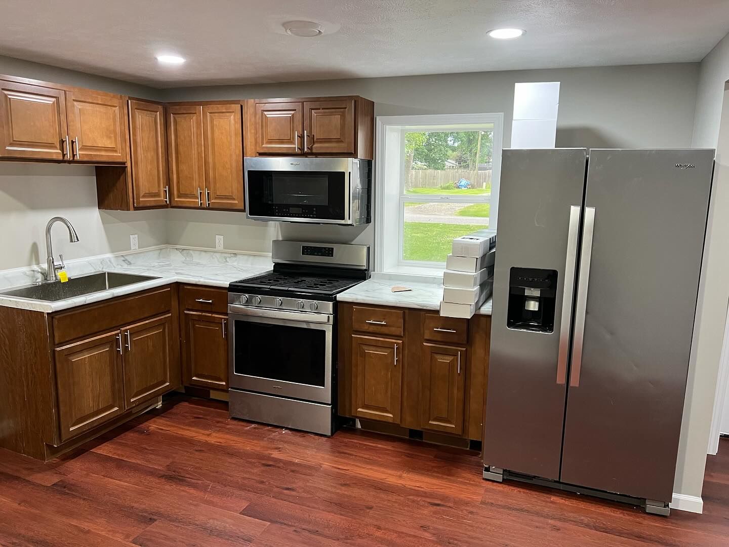 Kitchen with brown cabinets, stainless steel appliances, and wood floors.