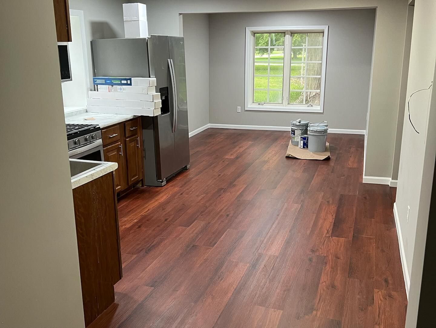 Kitchen and dining area with dark wood flooring, stainless steel fridge, and gray walls.