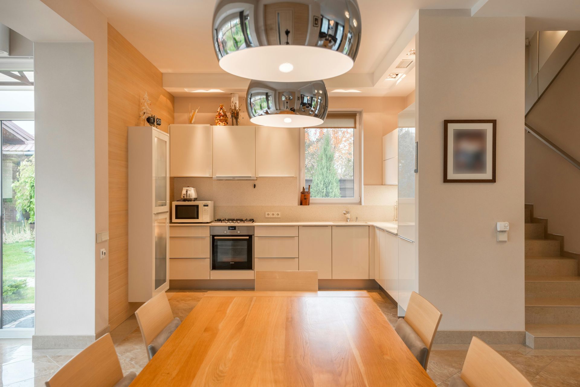 Bright modern kitchen and living area with gray tufted sofa, marble floors, and blue accents