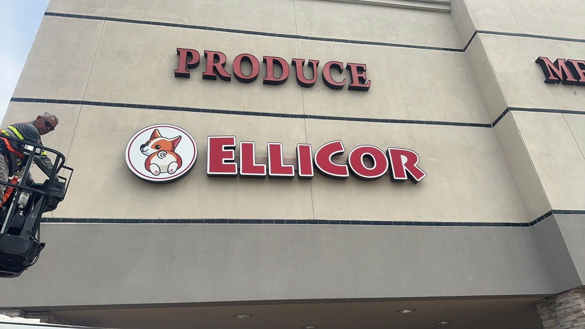 A sign for ellicor produce is being installed on the side of a building