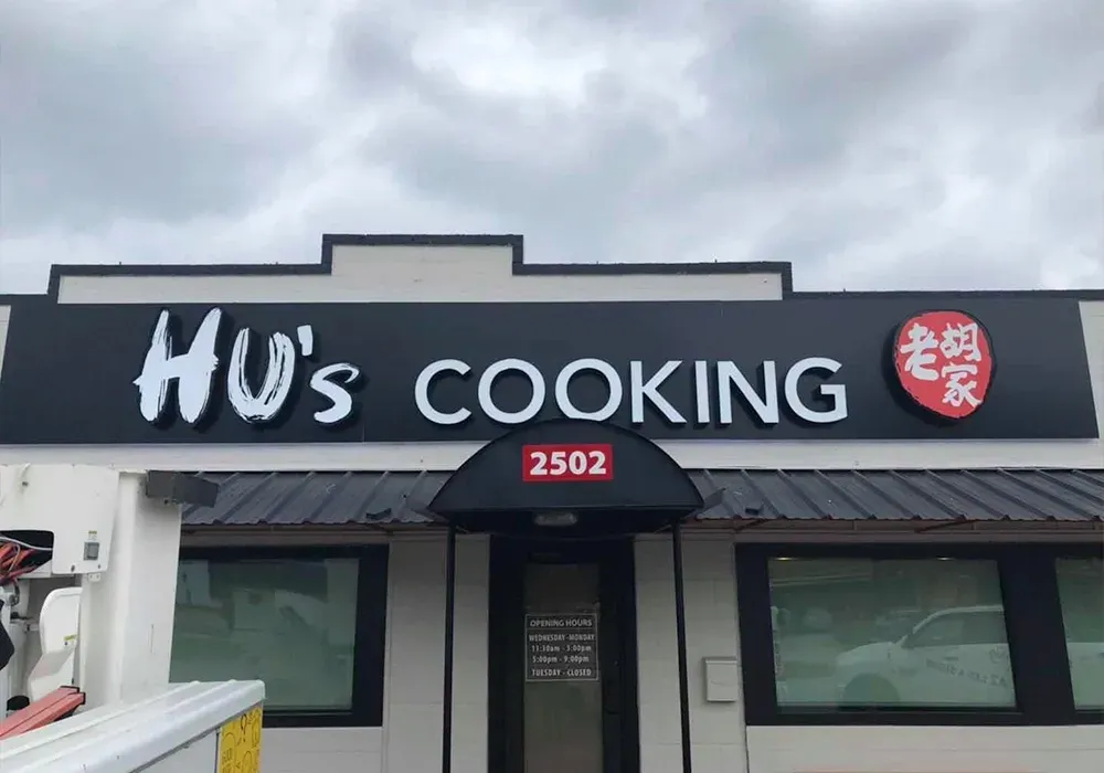 A building with a sign that says Hu 's Cooking on it.